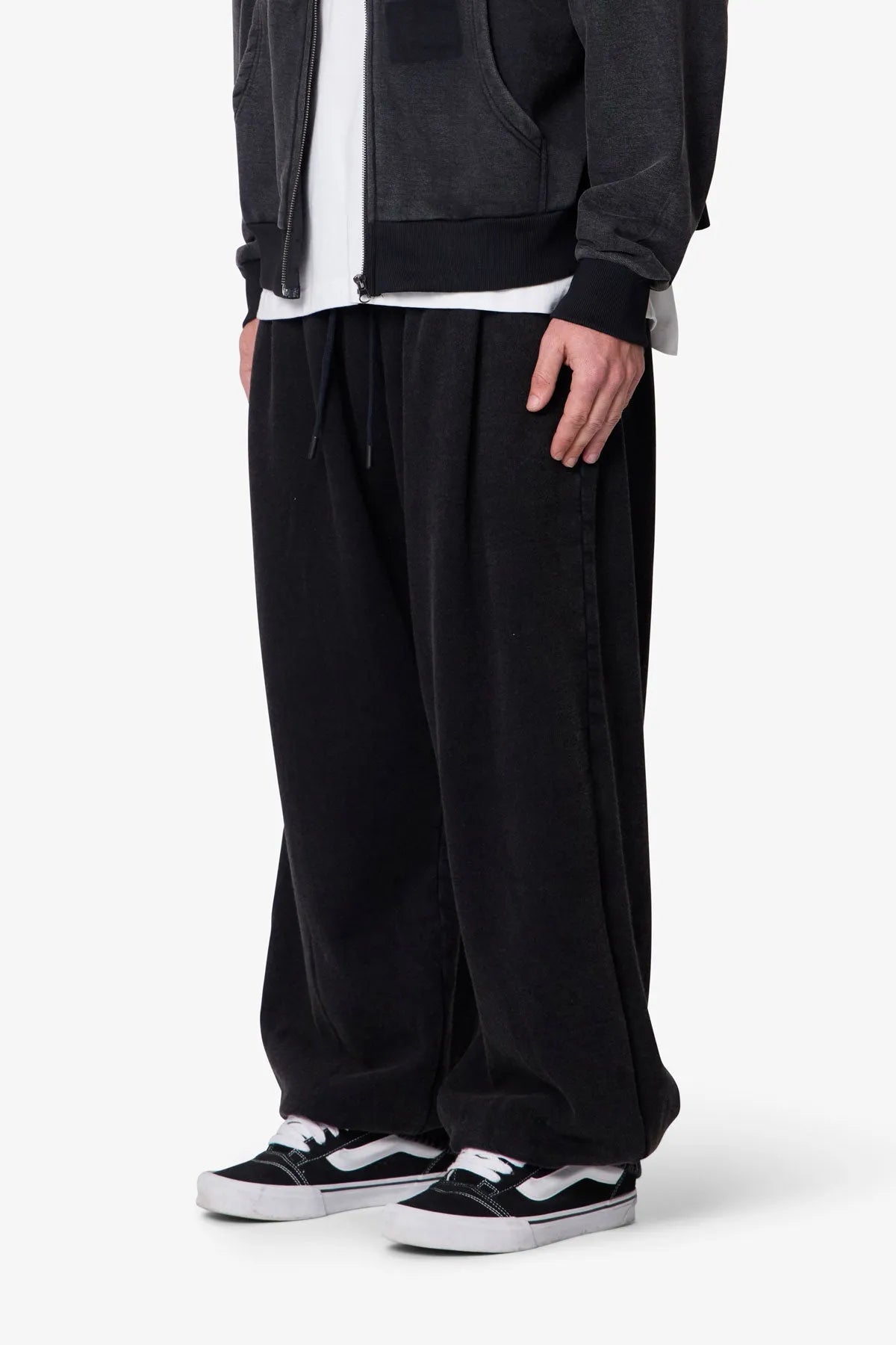 Person wearing black baggy sweatpants with a plain background