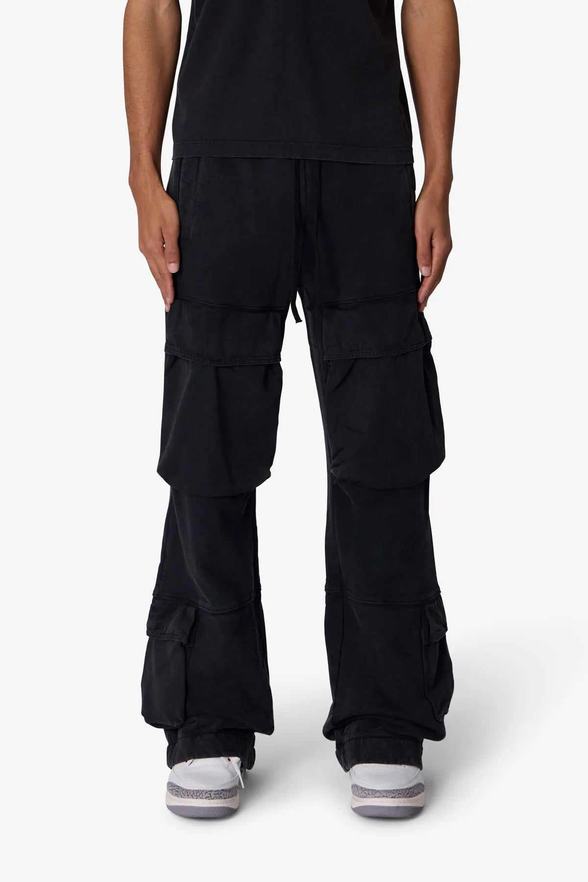 Person wearing black cargo pants on a white background