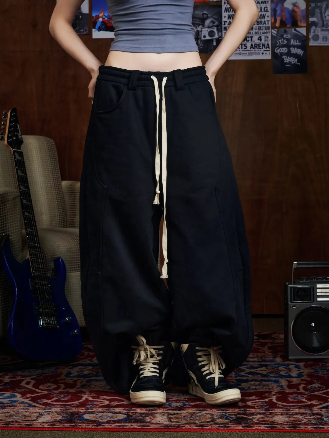 Person wearing black sweatpants with a drawstring in a room with musical instruments.