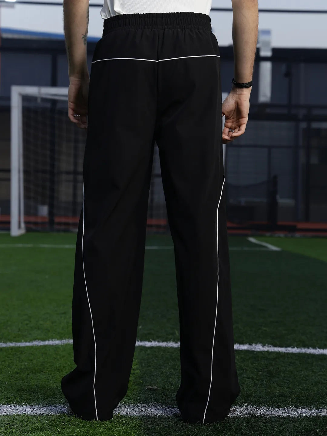 Person wearing black pants with white stripes on a sports field