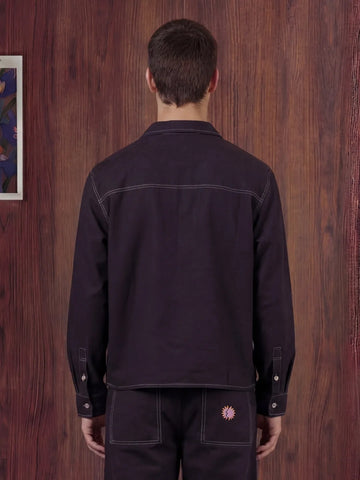 Person wearing a black shirt and pants against a wooden wall.