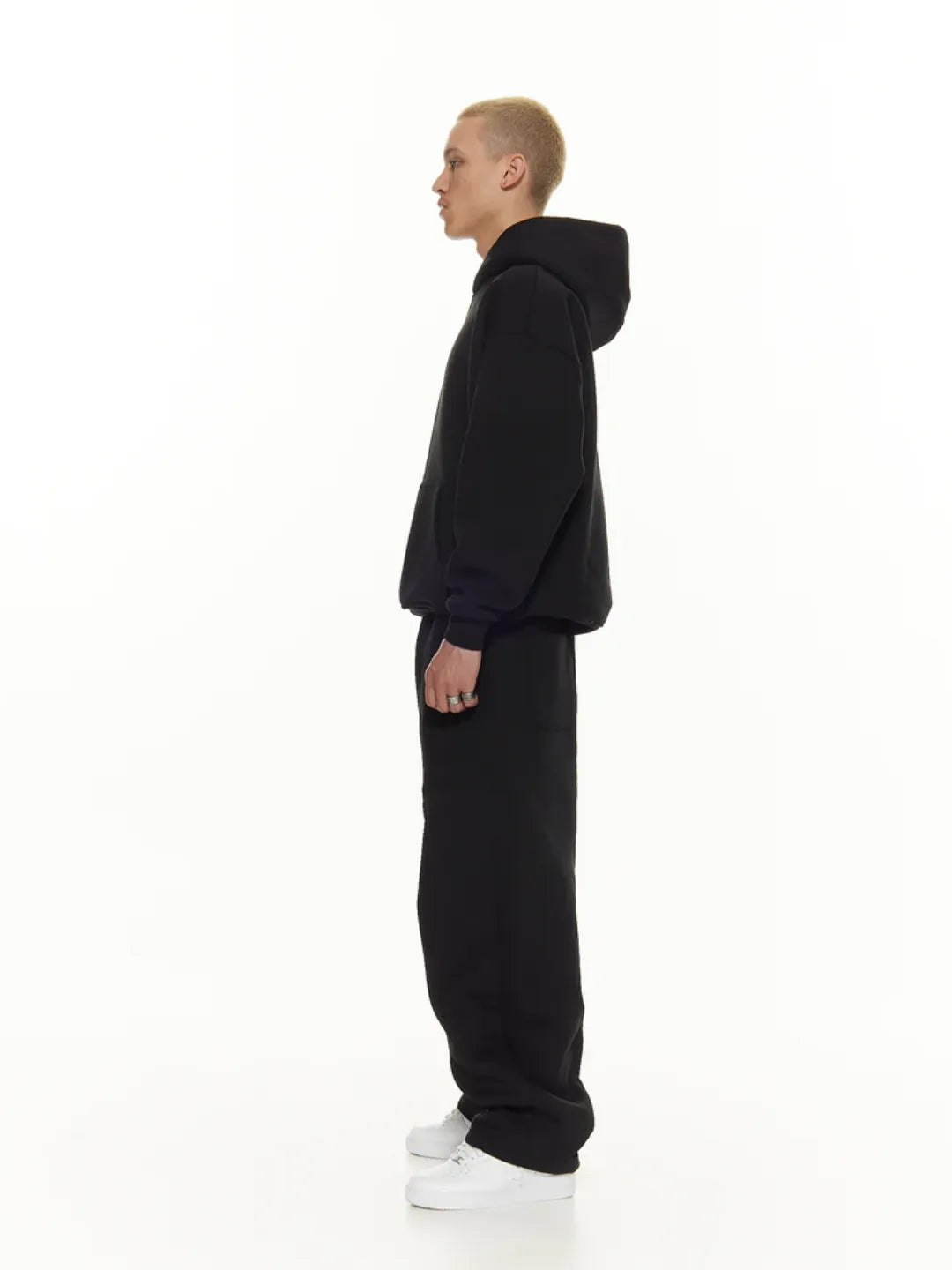 Person wearing a black hoodie and pants on a white background
