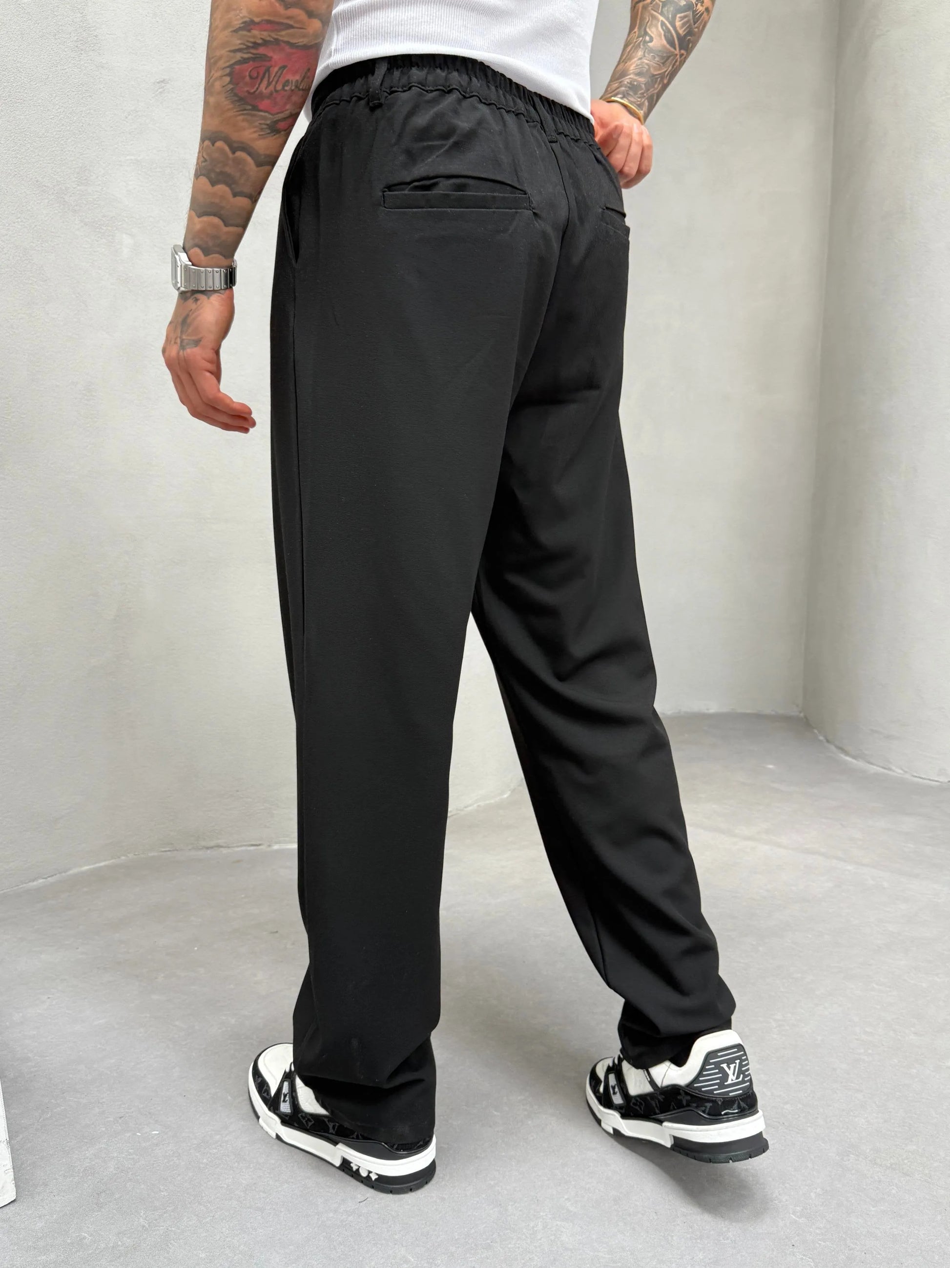 Person wearing black pleated office pants 