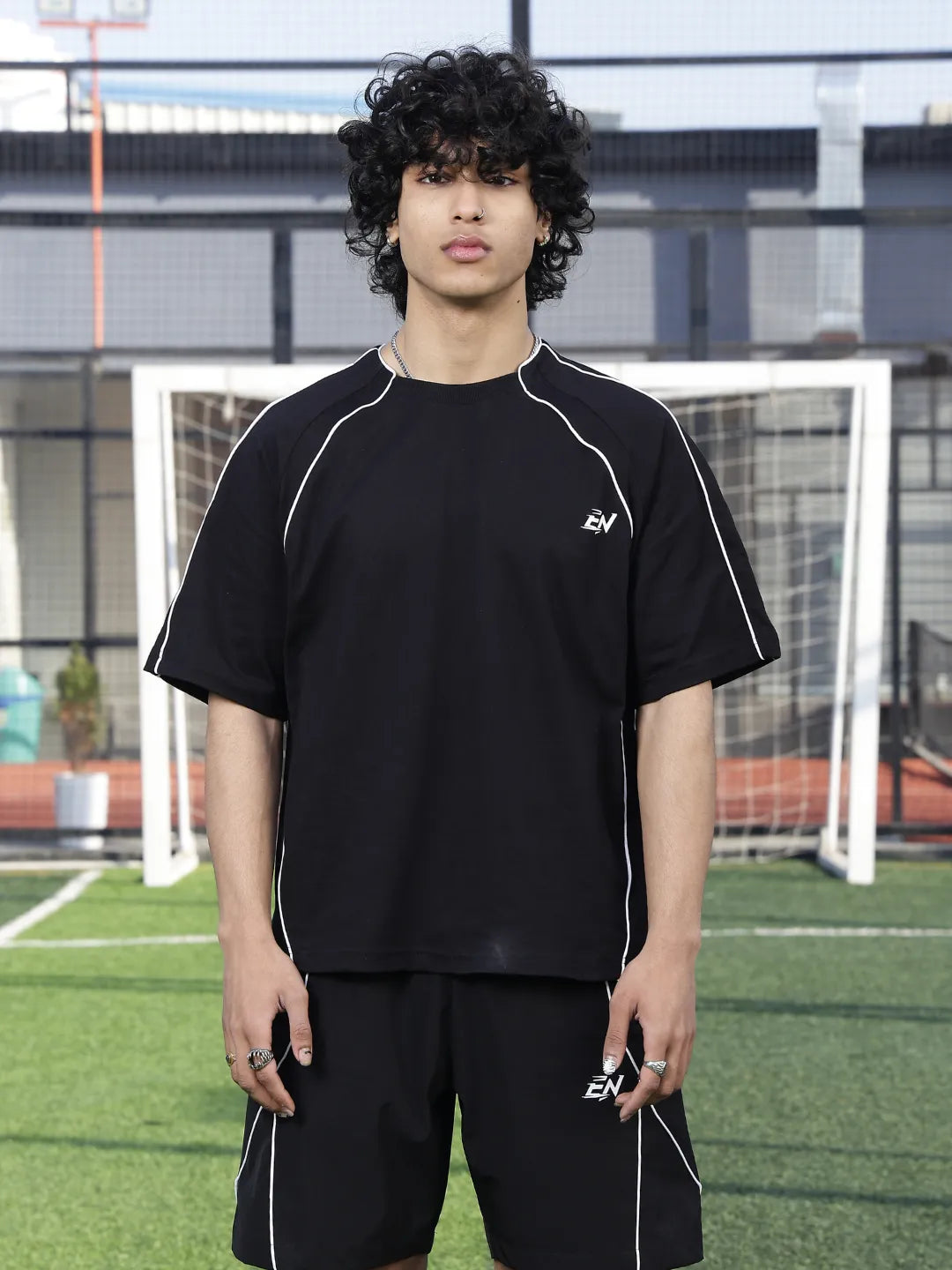 Person wearing a black sports t-shirt with a logo on a sports field