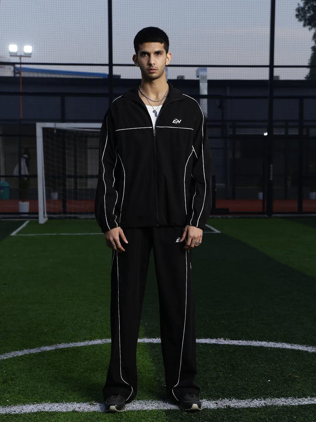 Person wearing a black tracksuit on a sports field