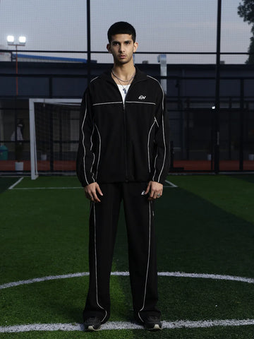 Person wearing a black tracksuit on a sports field