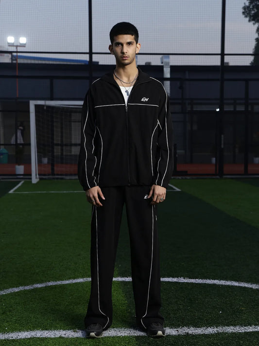 Person wearing a black tracksuit on a sports field