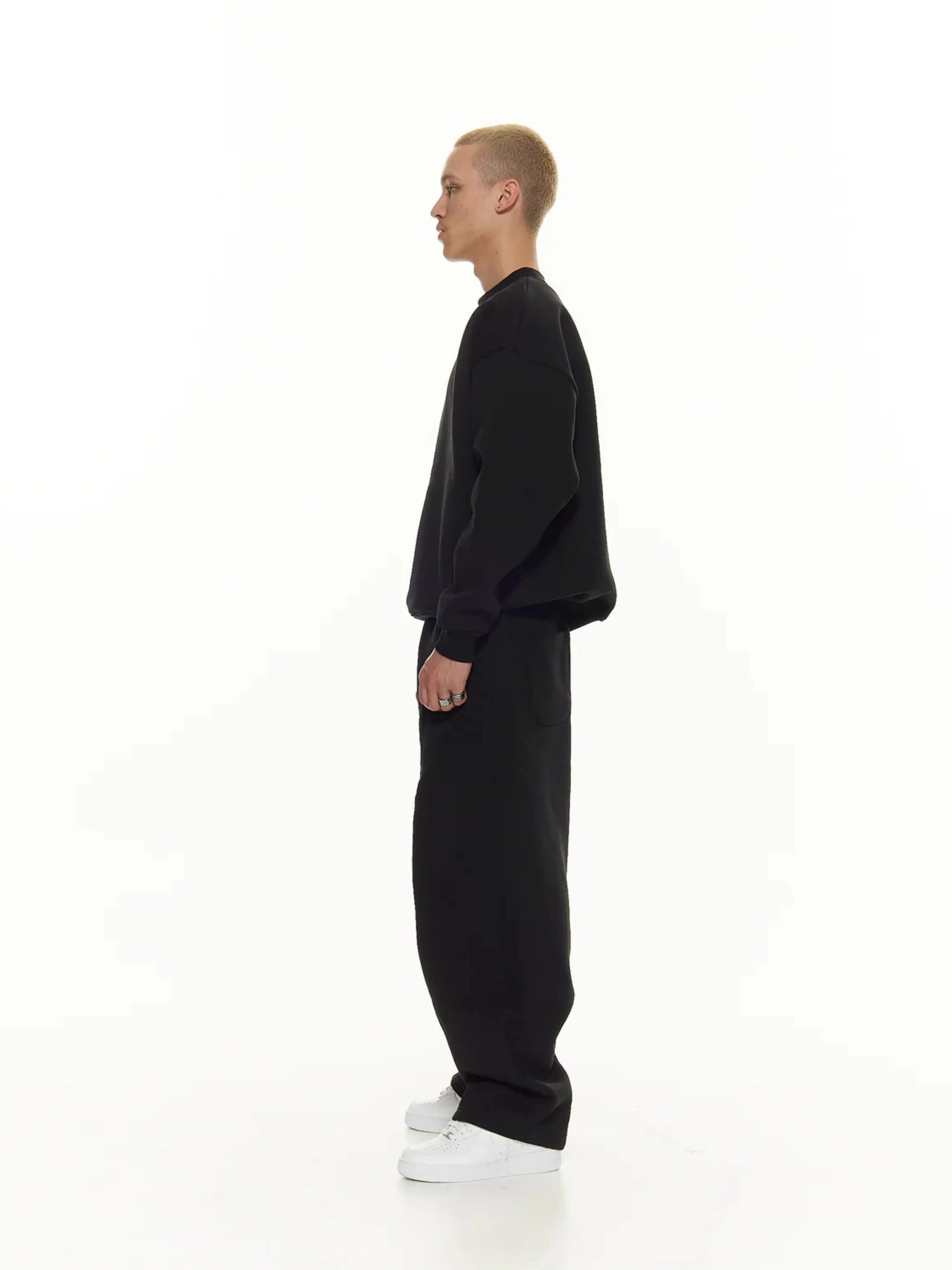 Person wearing a black sweatshirt and sweatpants set on a white background