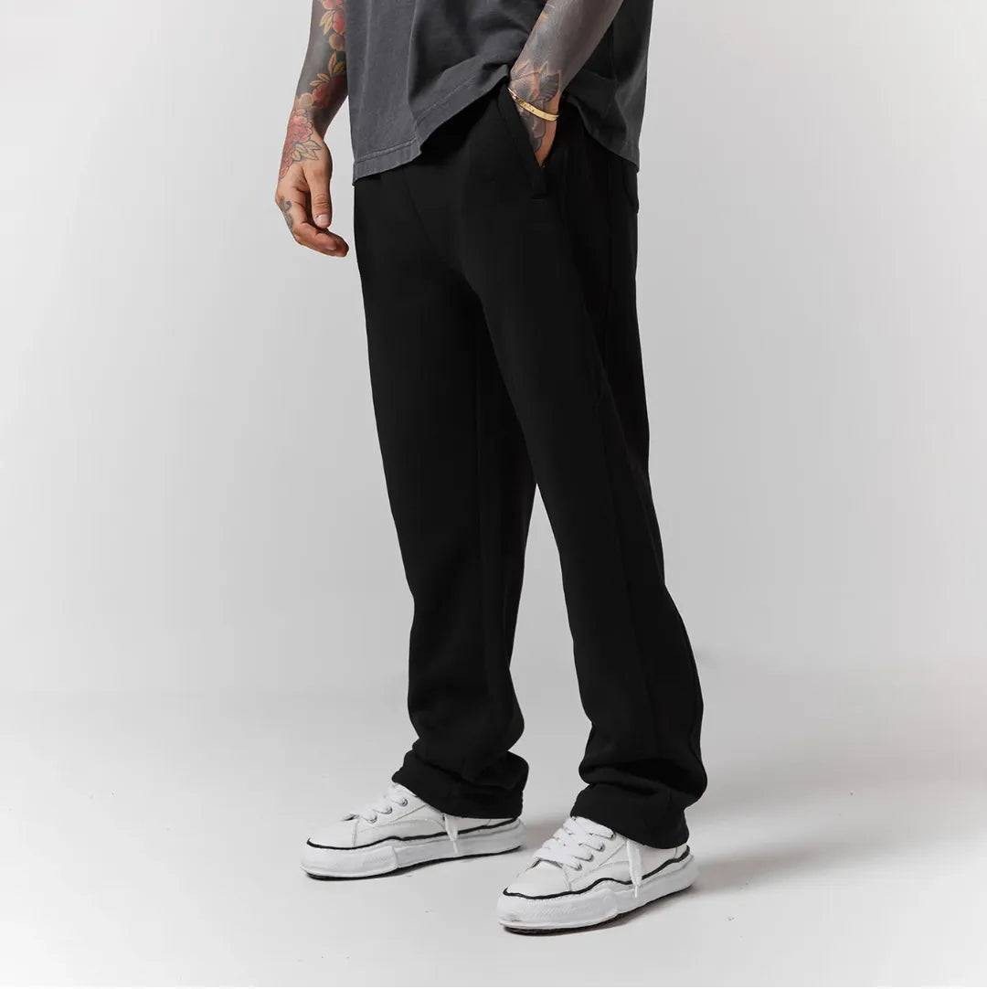 Person wearing black jogger and white sneakers on a plain background