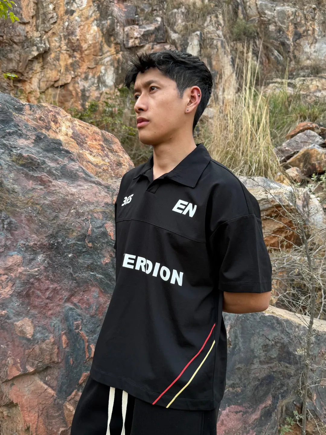 Person wearing a black shirt with branding in an outdoor setting
