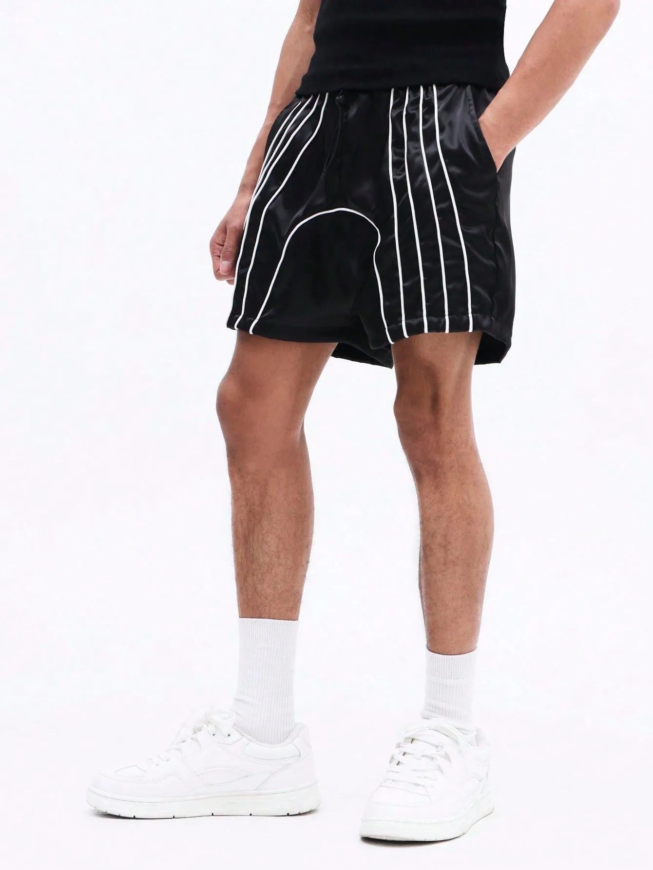 Black shorts with white stripes worn by a person on a plain background