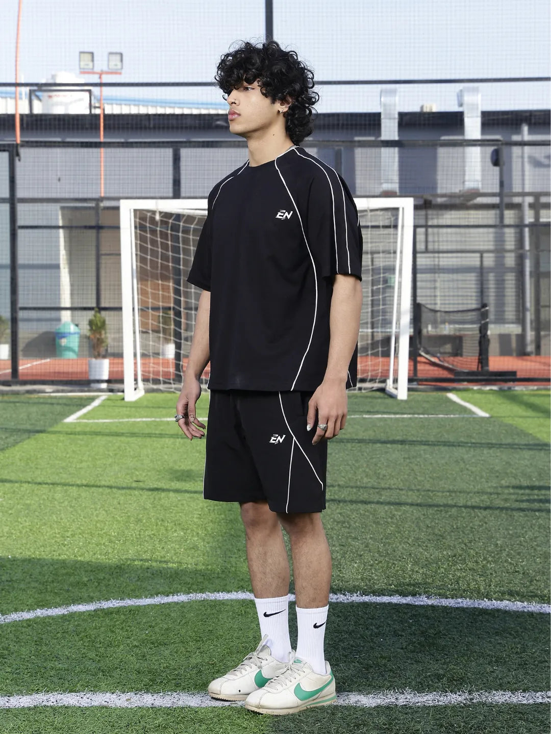 Person wearing black sports outfit with visible brand logo on a sports field.