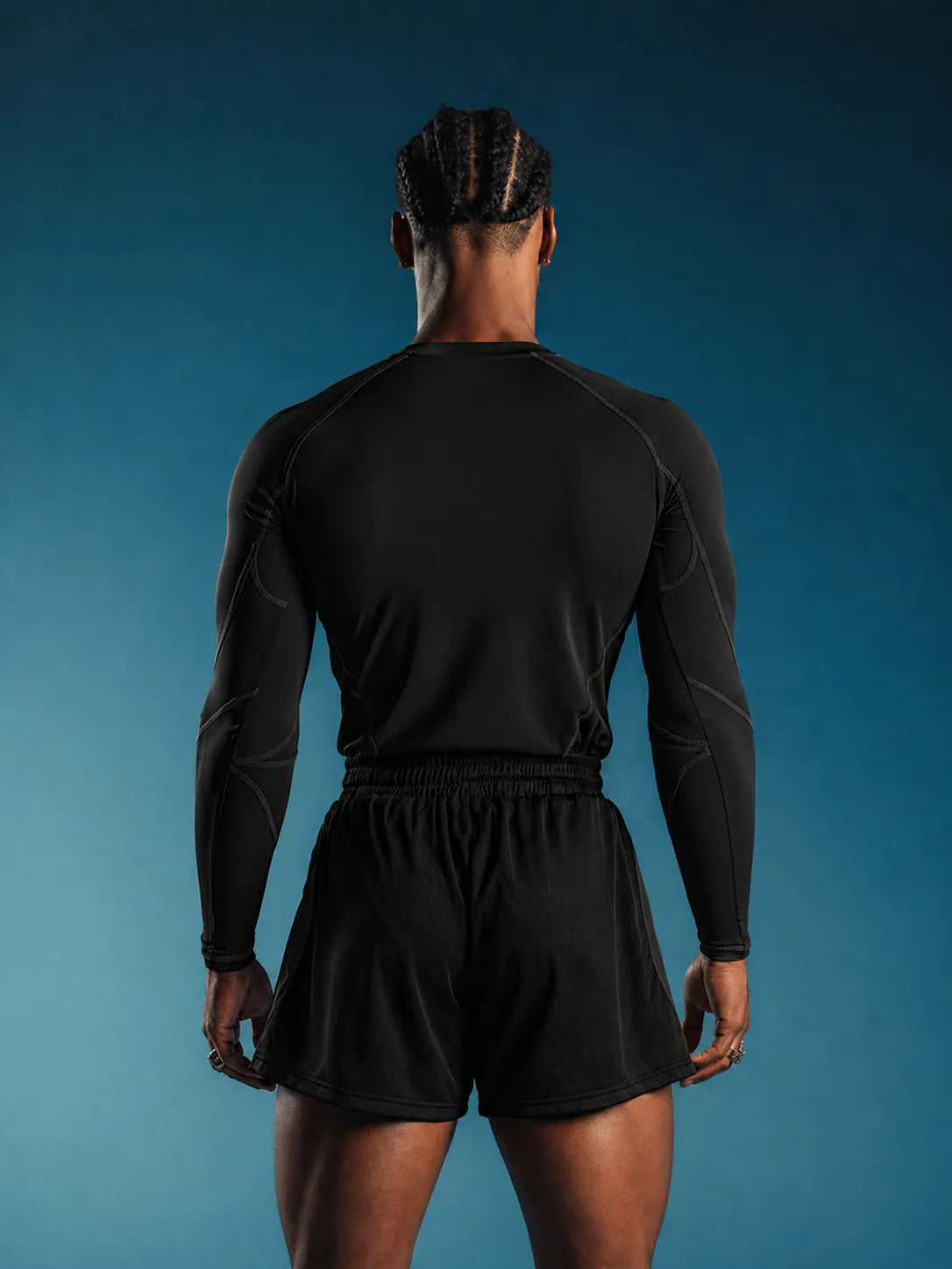 Person wearing a black Compression Full Sleeve T-shirt and shorts on a blue background