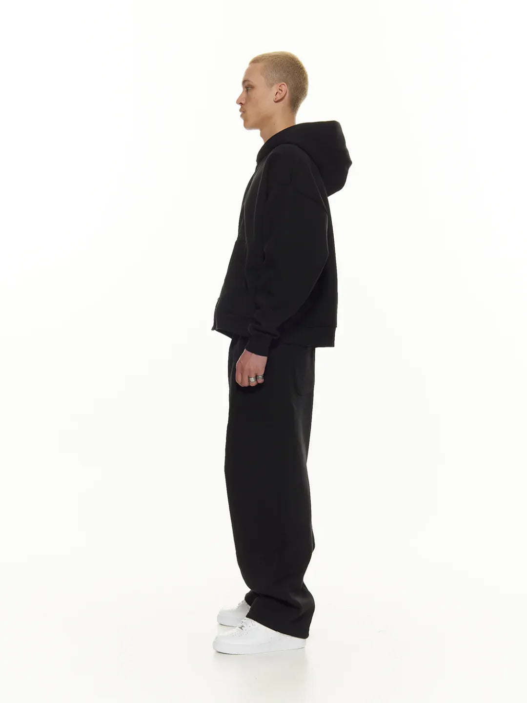 Person wearing a black zip-up jacket on a white background