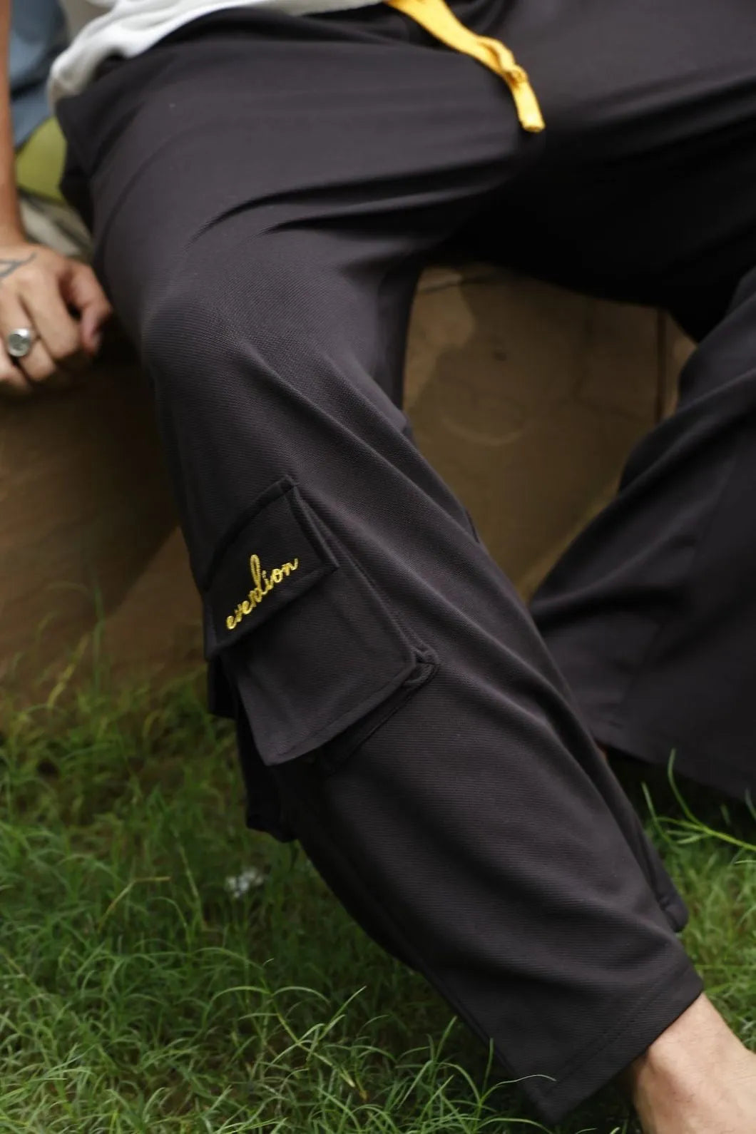 Person wearing black pants with a visible brand logo on grass