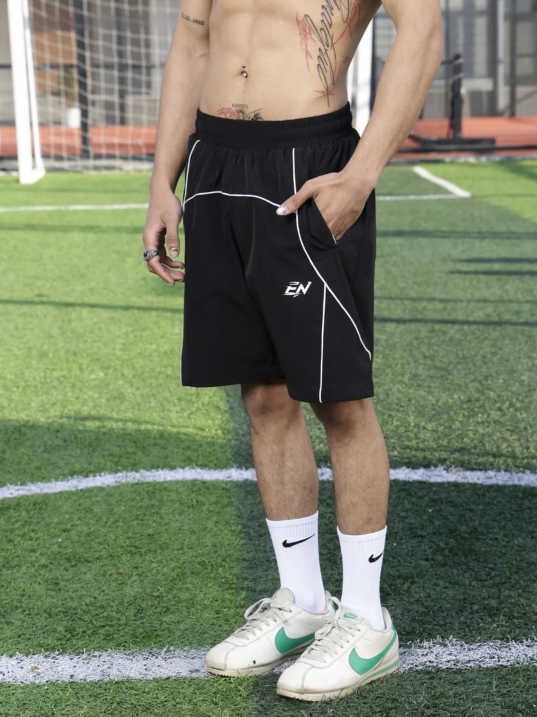 Person wearing black shorts with a logo on a sports field