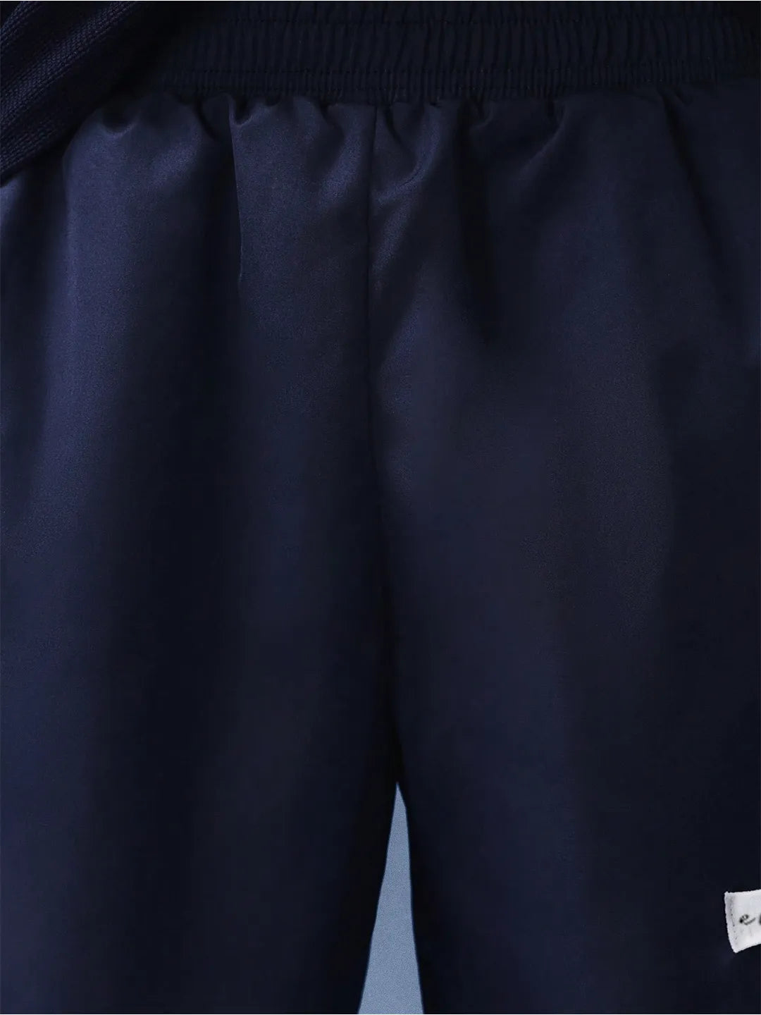 Close-up of dark blue pants with a brand label on the leg.