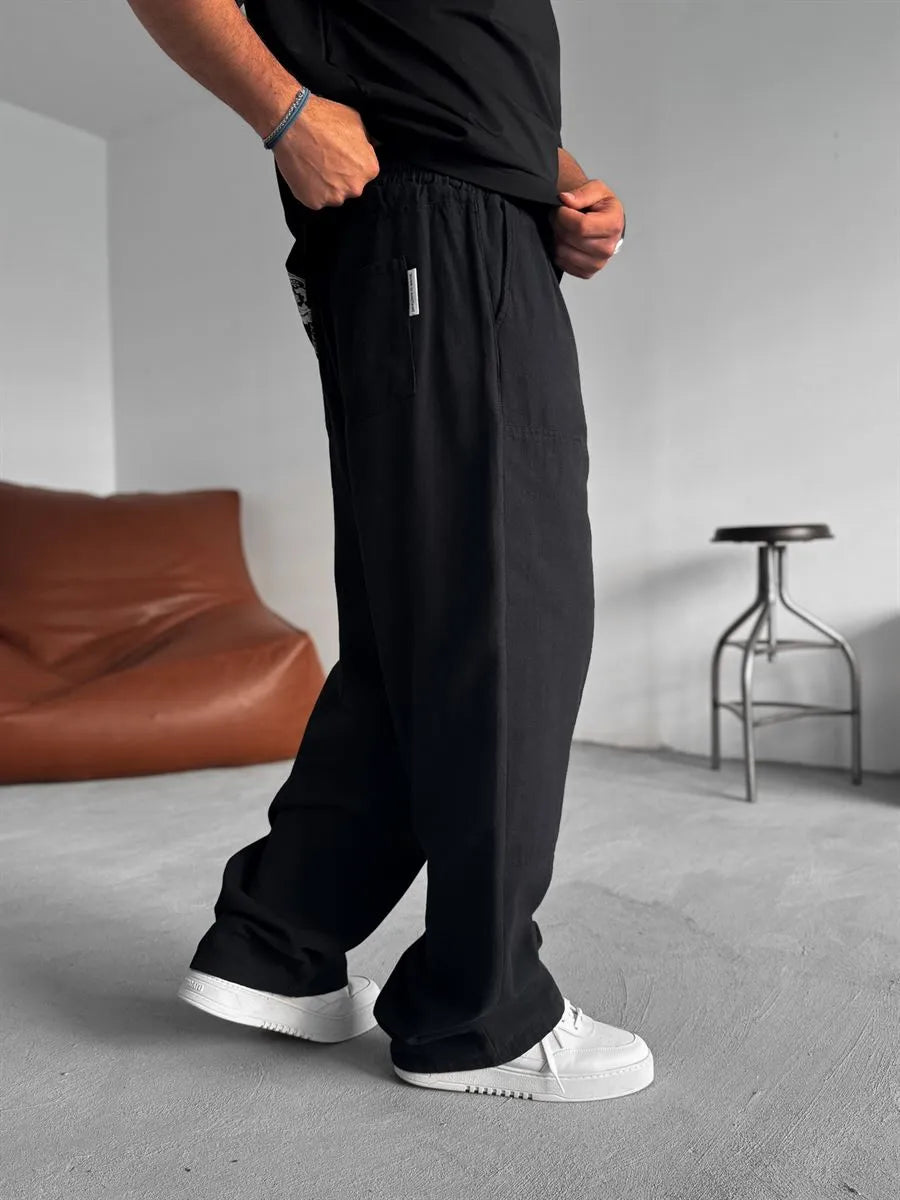 Person wearing black linen pants and white shoes in a minimal indoor setting