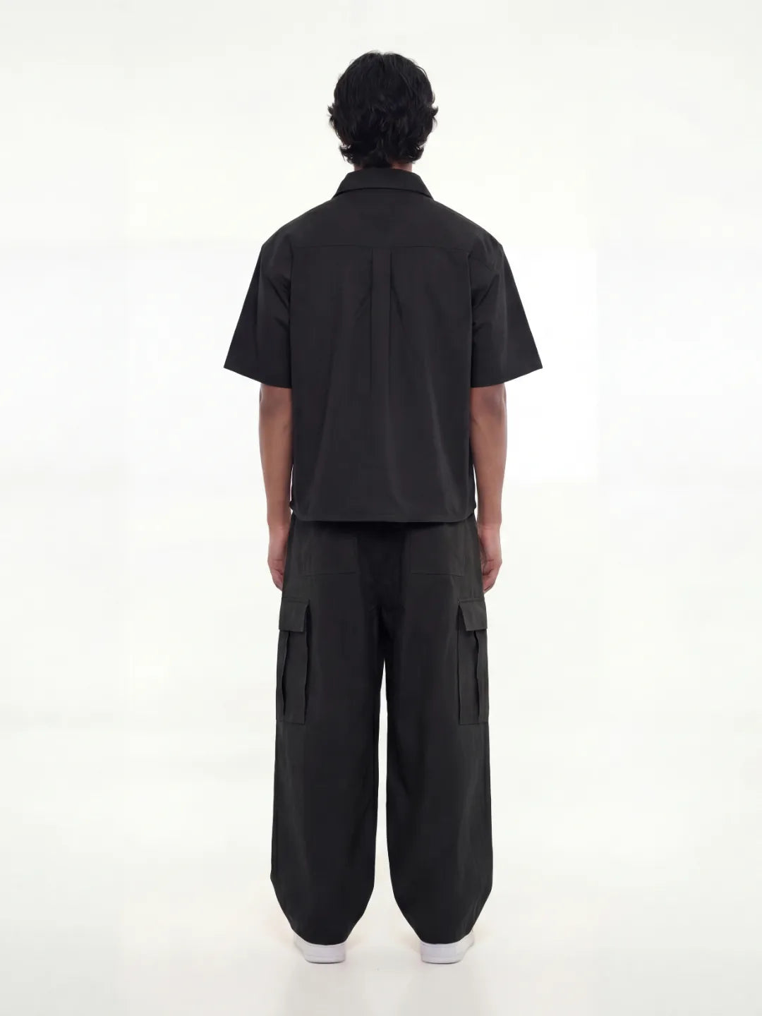 Person wearing a black shirt with cargo pants on a white background