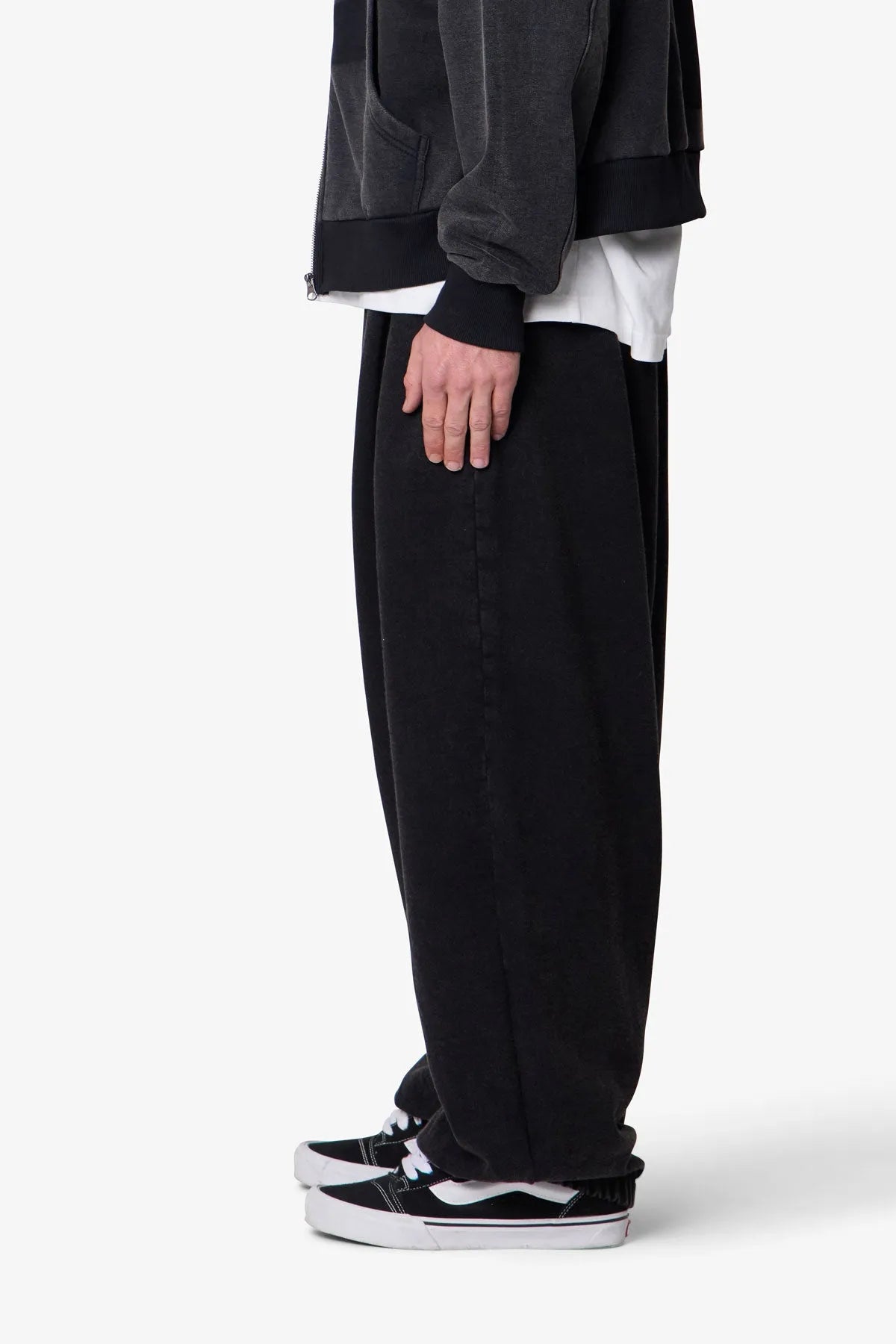 Person wearing black baggy sweatpants with a plain background