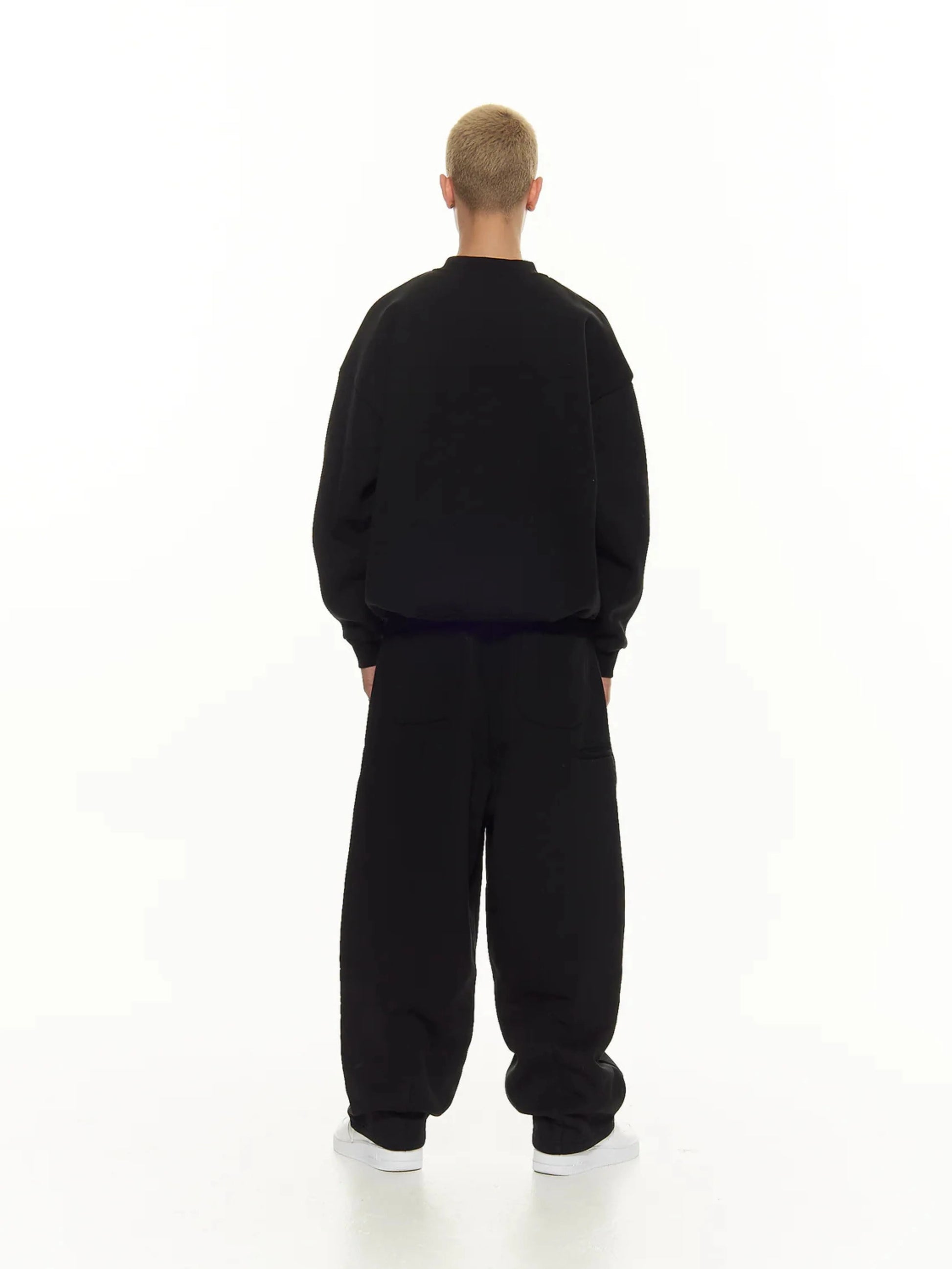 Person wearing a black sweatshirt and sweatpants set on a white background