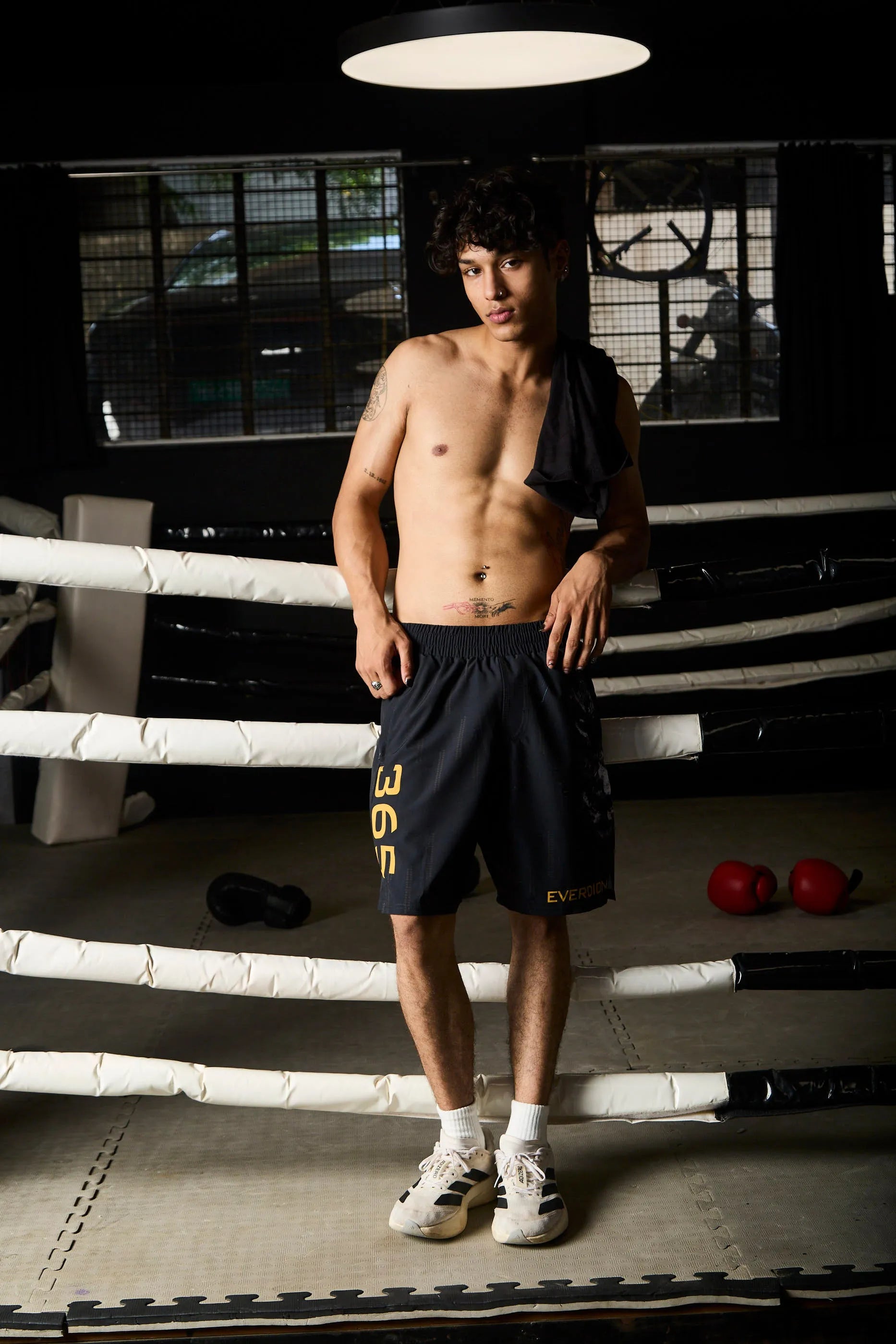 Man standing in a boxing ring wearing black shorts with '365' printed on them.