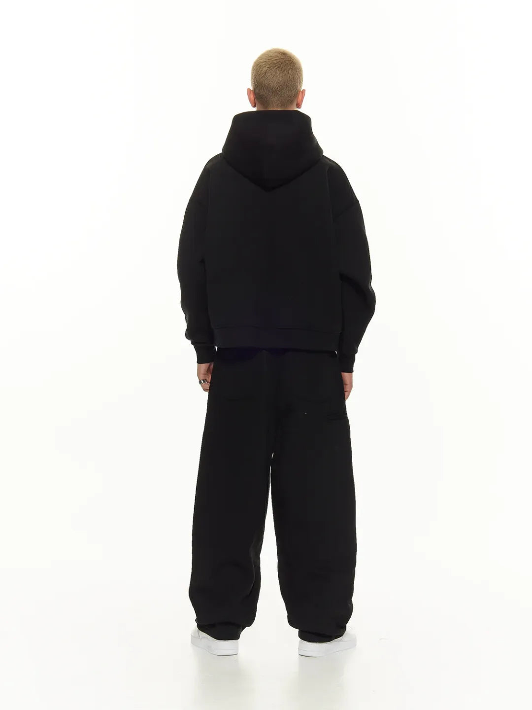 Person wearing a black hoodie and black pants on a white background