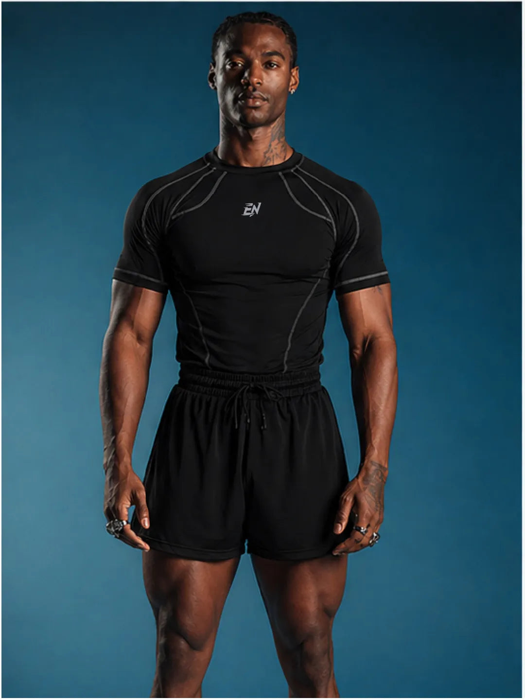 Man wearing a black athletic t-shirt with a brand logo on a blue background