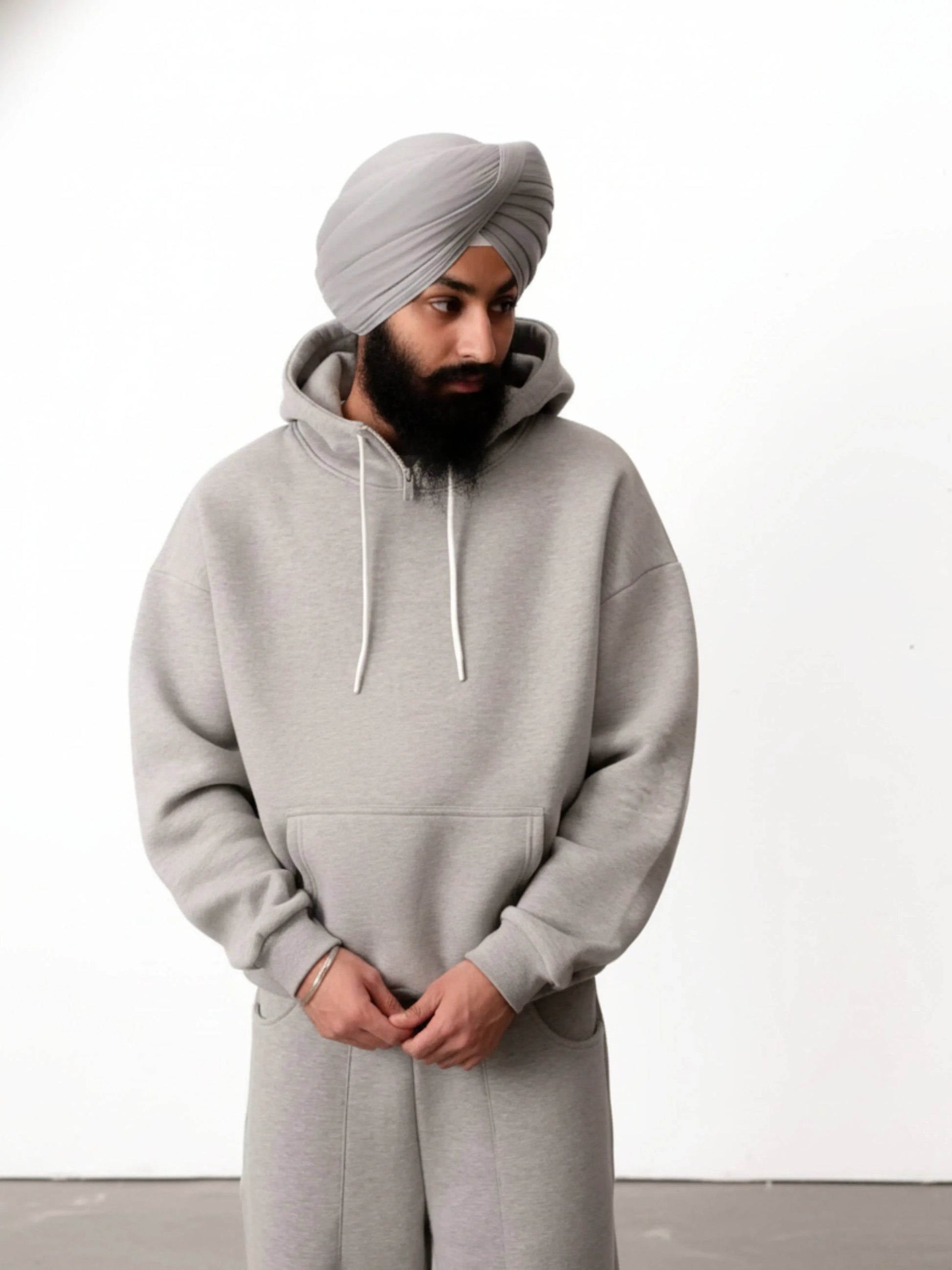 Man wearing a grey hoodie and turban against a white background