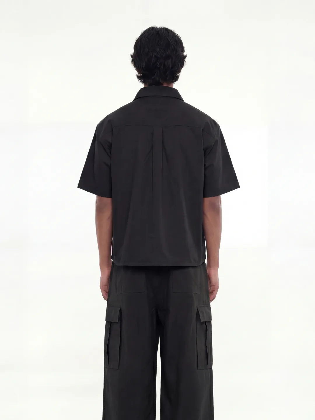 Person wearing a black outfit with cargo pants on a white background