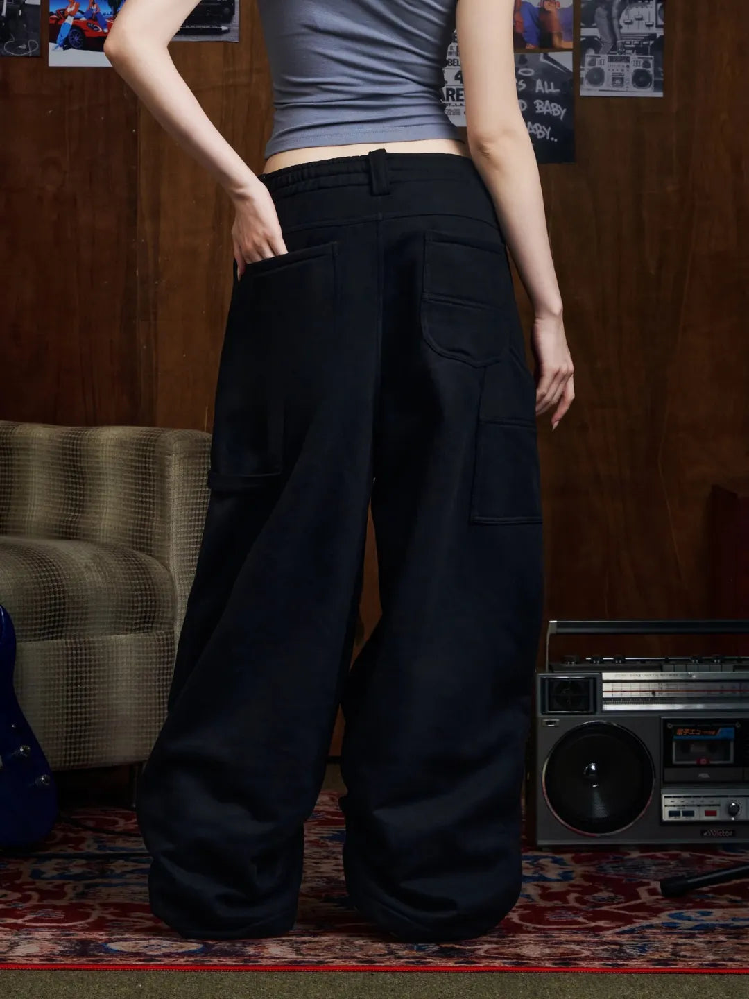 Person wearing black sweatpants in a room with a wooden wall and vintage boombox.