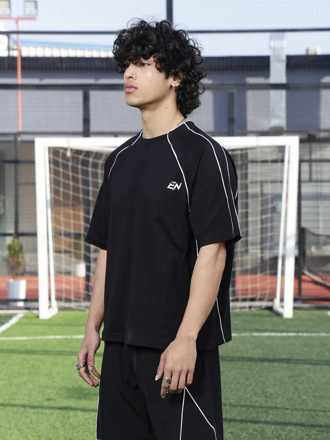 Person wearing a black outfit with 'EN' logo on a sports field