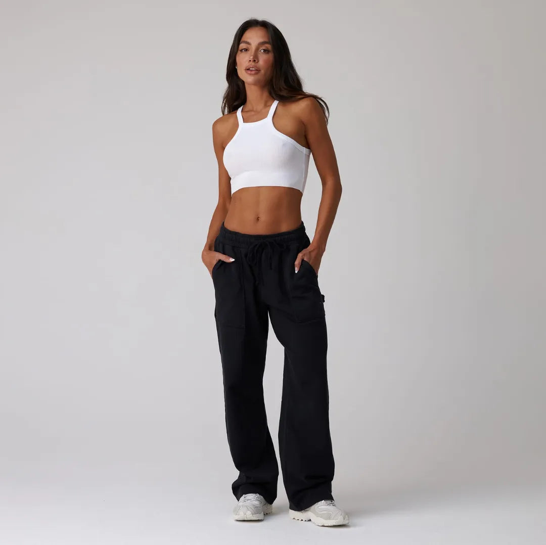 Person wearing black drawstring sweatpant on a plain background