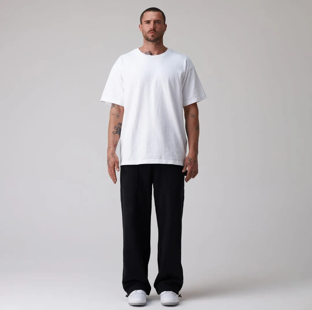 Man wearing a plain white t-shirt and black sweatpants on a light grey background
