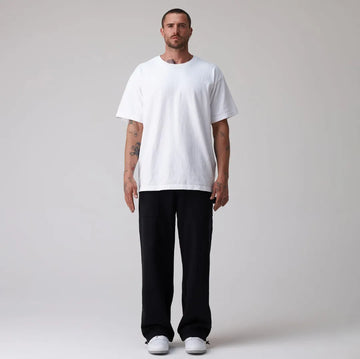 Man wearing a plain white t-shirt and black sweatpants on a light grey background