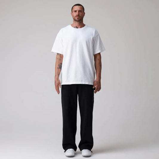 Man wearing a plain white t-shirt and black sweatpants on a light grey background