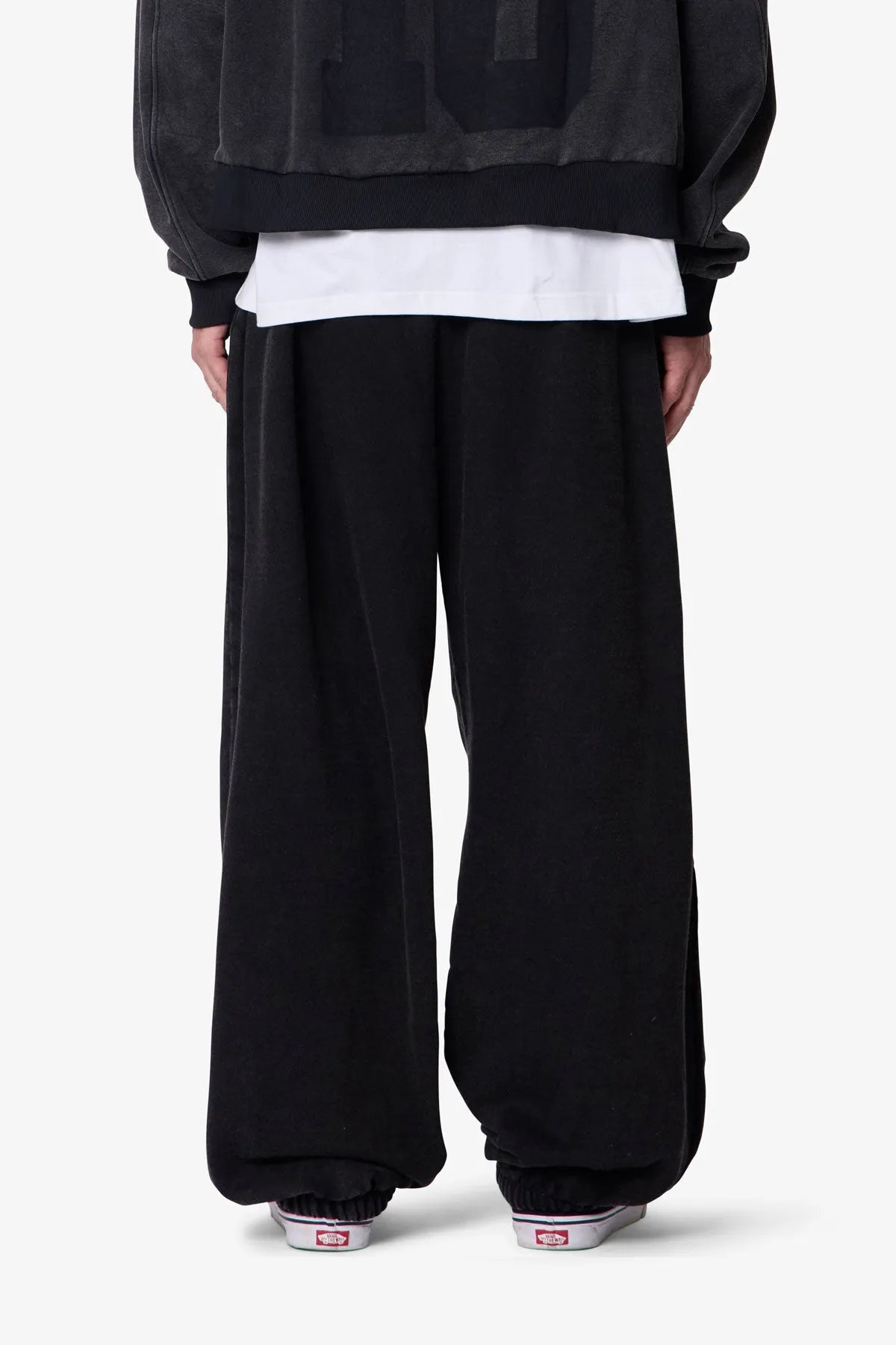 Person wearing black baggy sweatpants with a plain background