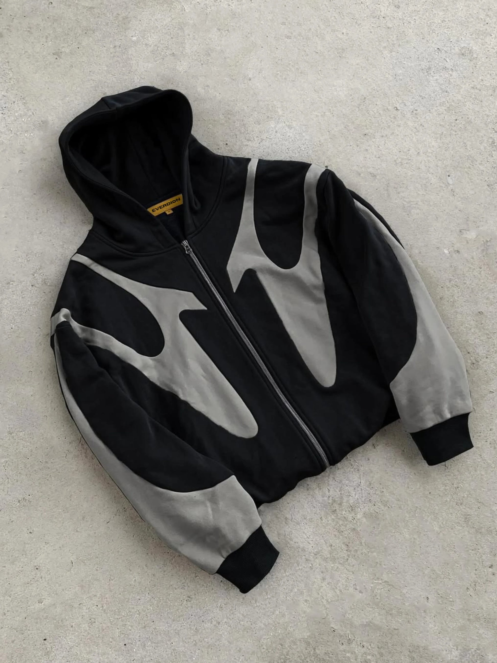 Black and grey hoodie with a zipper on a light grey surface