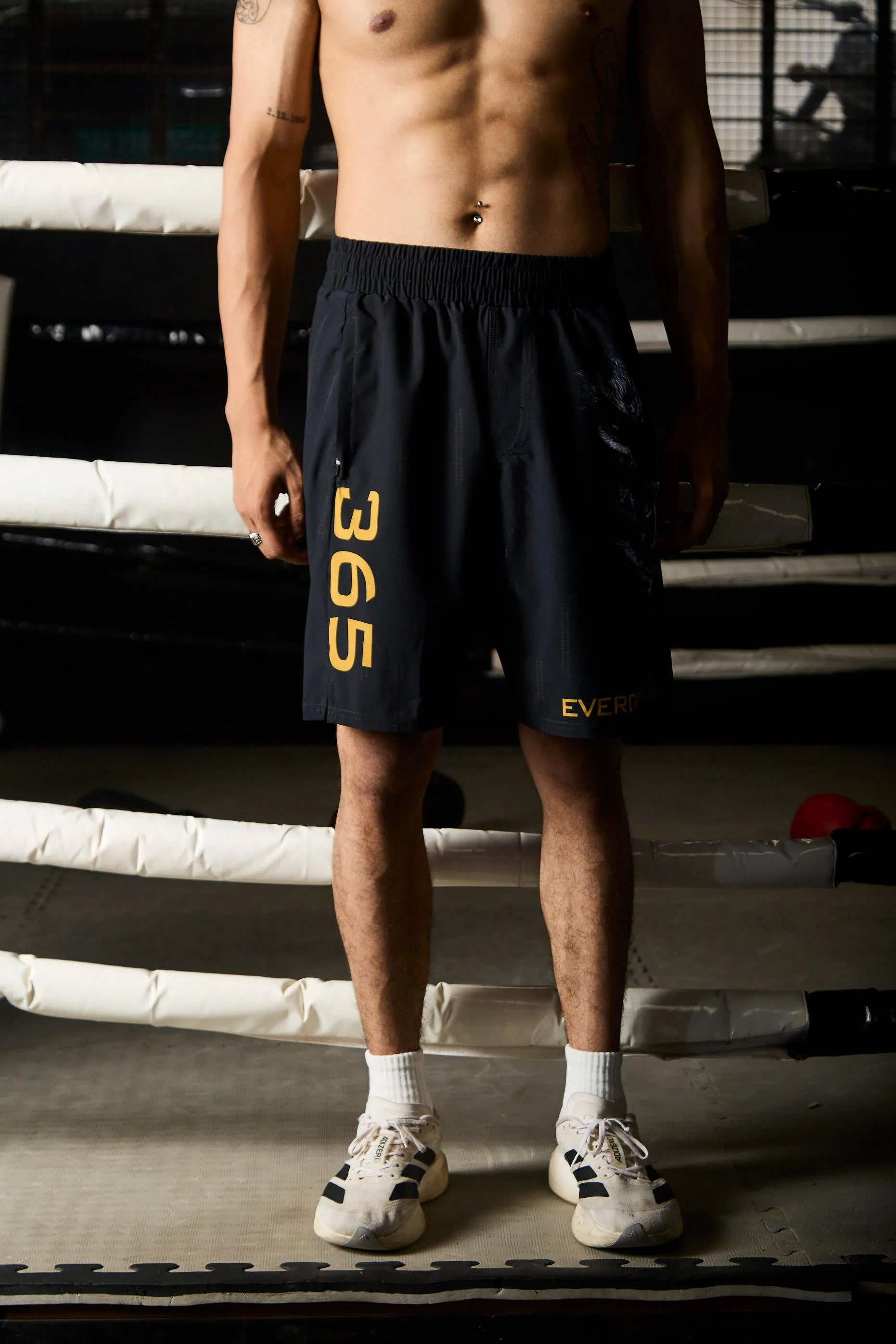 Person wearing black shorts with yellow text in a boxing ring.