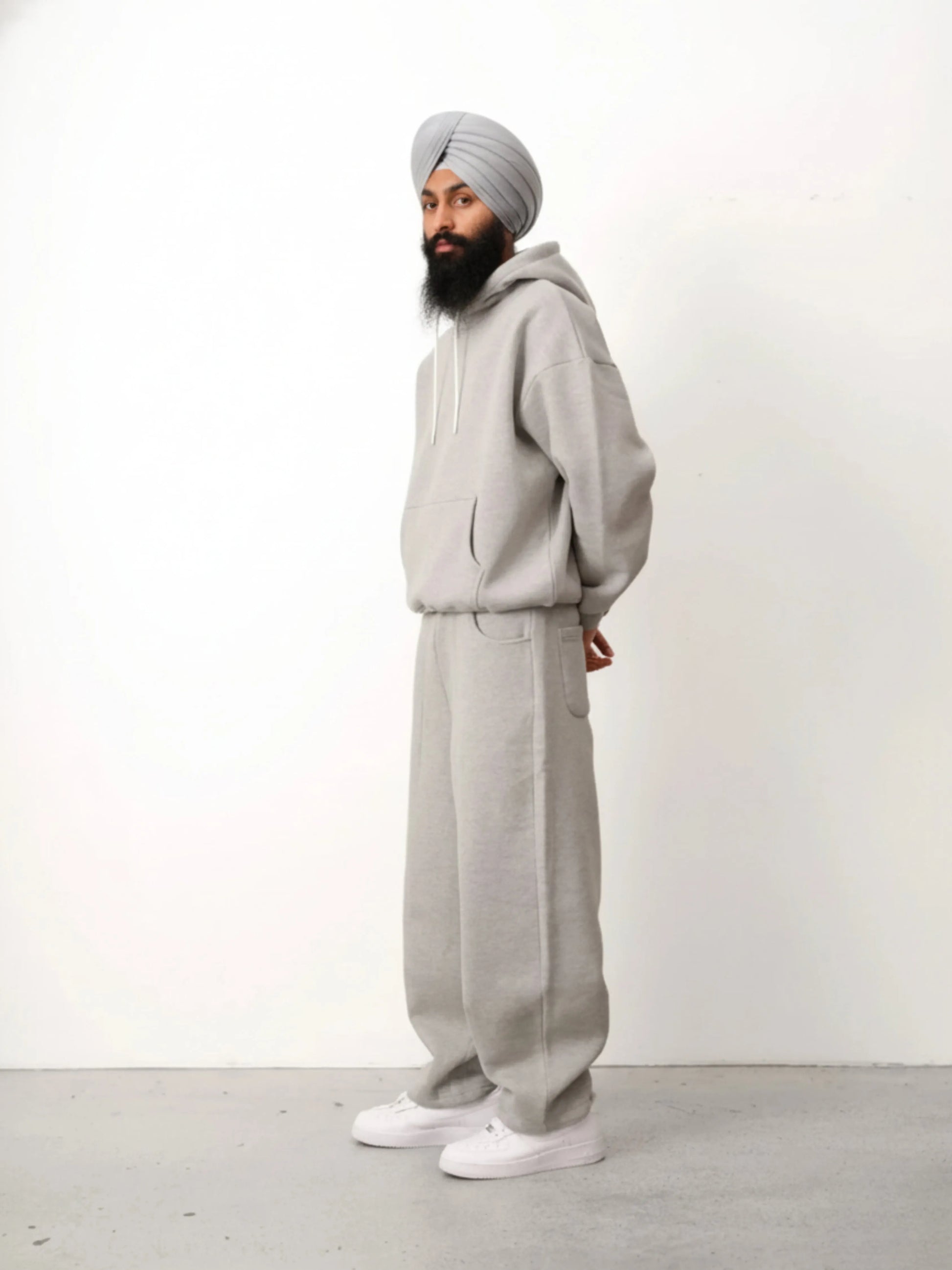 Person wearing a grey tracksuit and turban against a white background