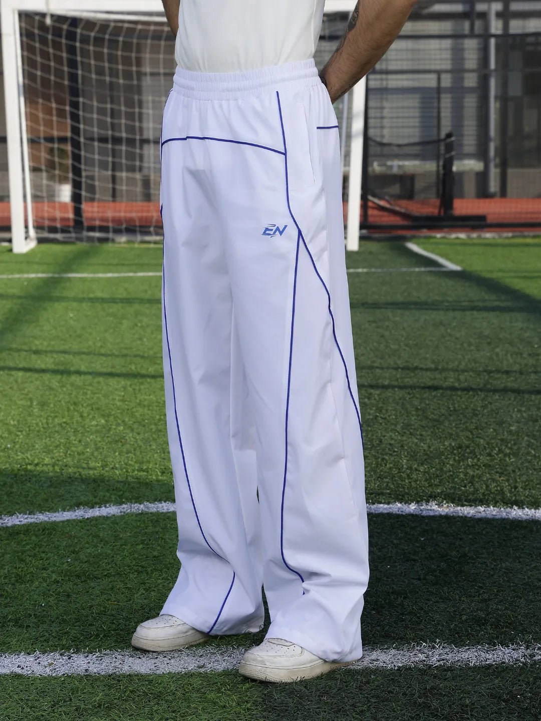 Person wearing white pants with a logo on a sports field