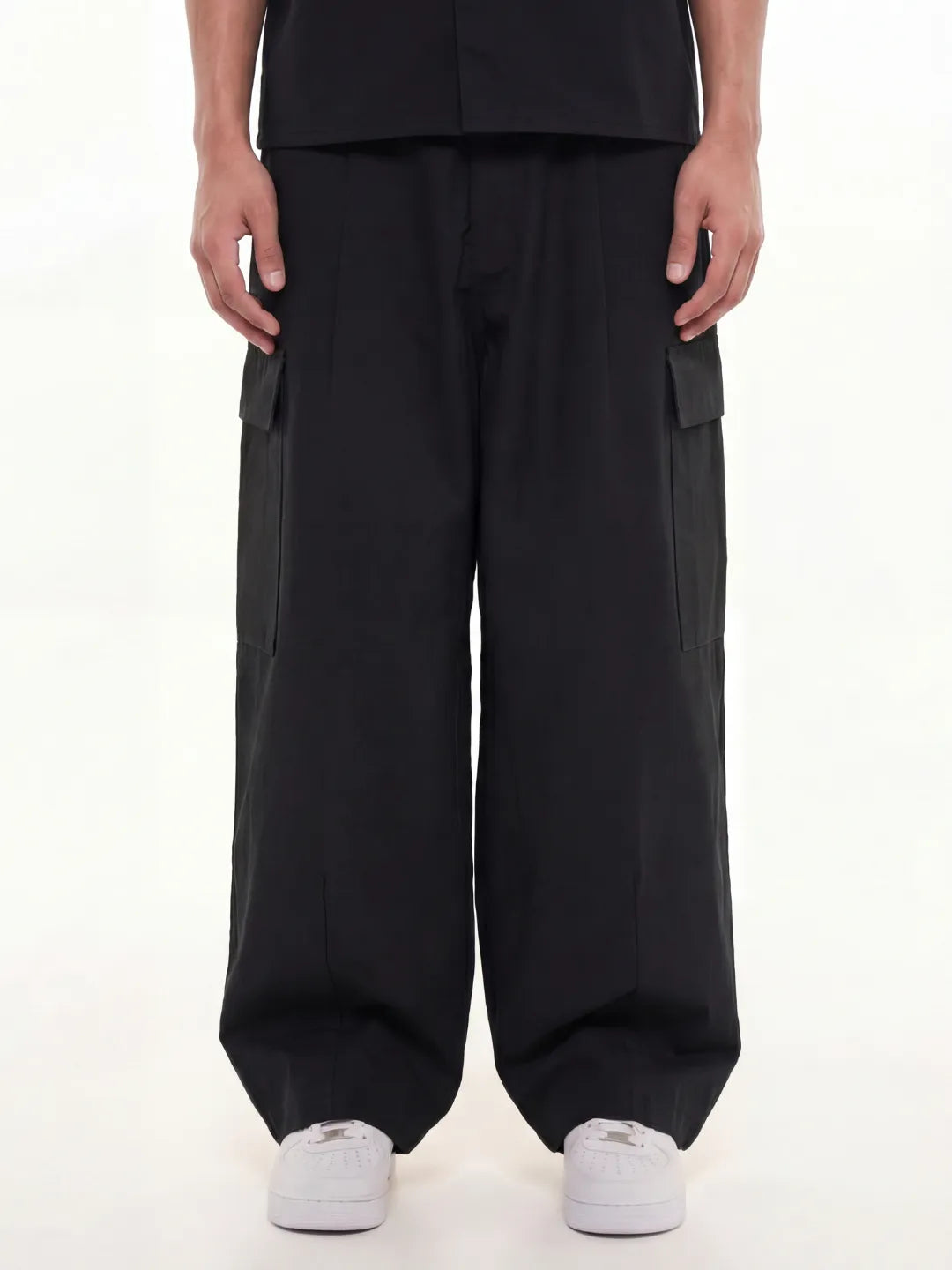 Person wearing black cargo pants and shirt on a white background