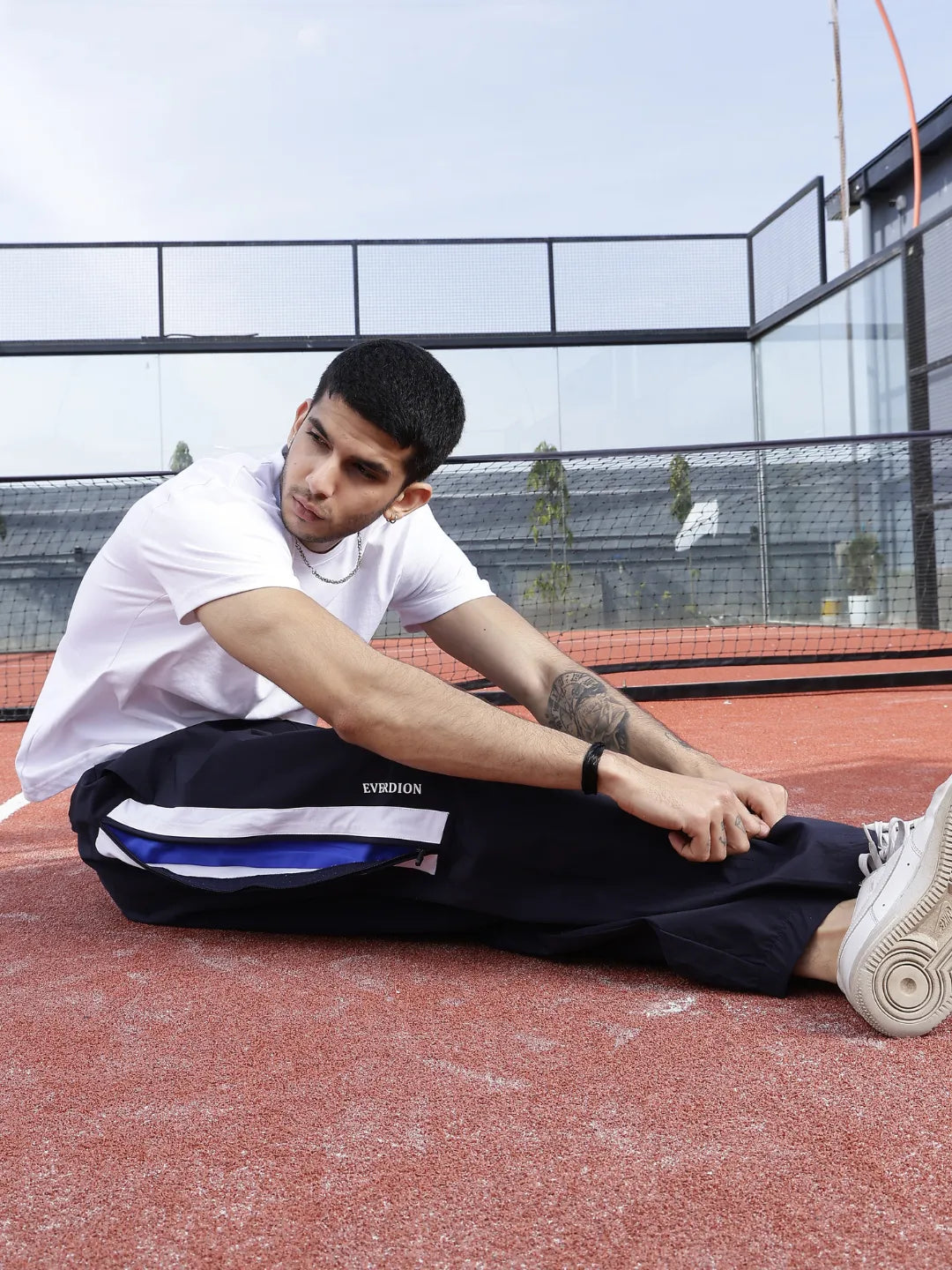 Person wearing navy blue sports pants with white stripes and 'Everdion' branding on a tennis court.