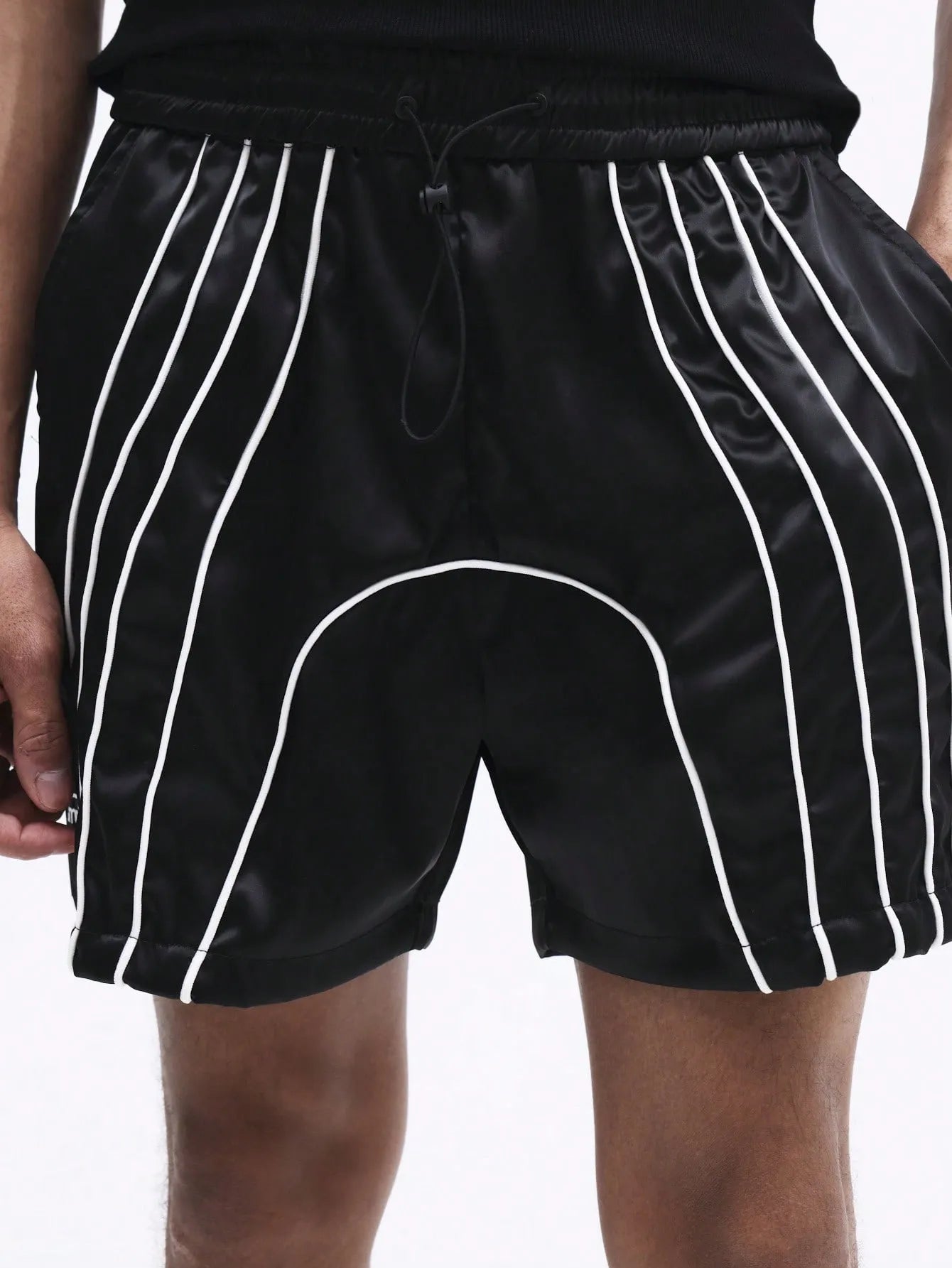 Black shorts with white stripes worn by a person on a plain background
