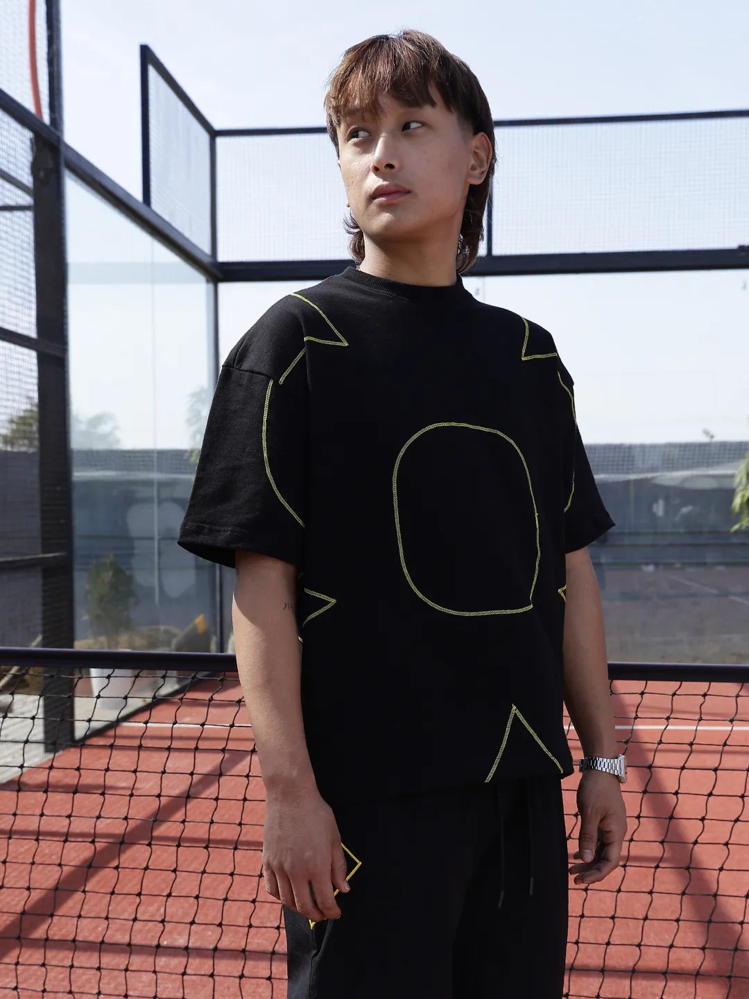 Person wearing a black t-shirt with geometric designs on a sports court