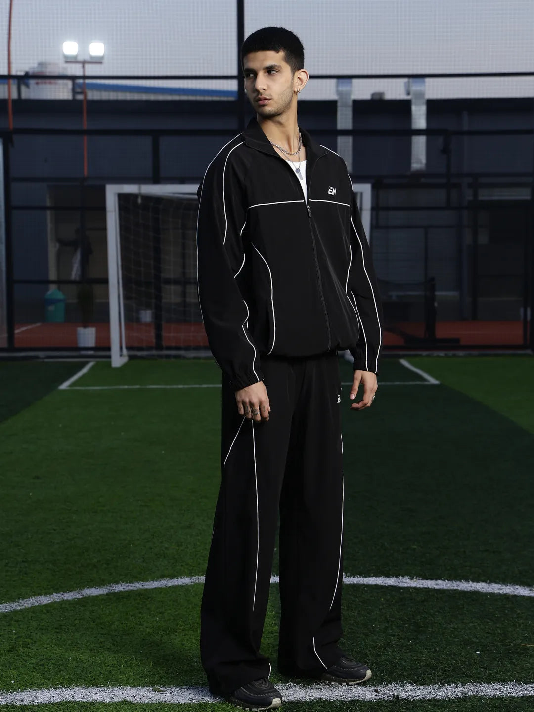 Man wearing a black tracksuit on a sports field