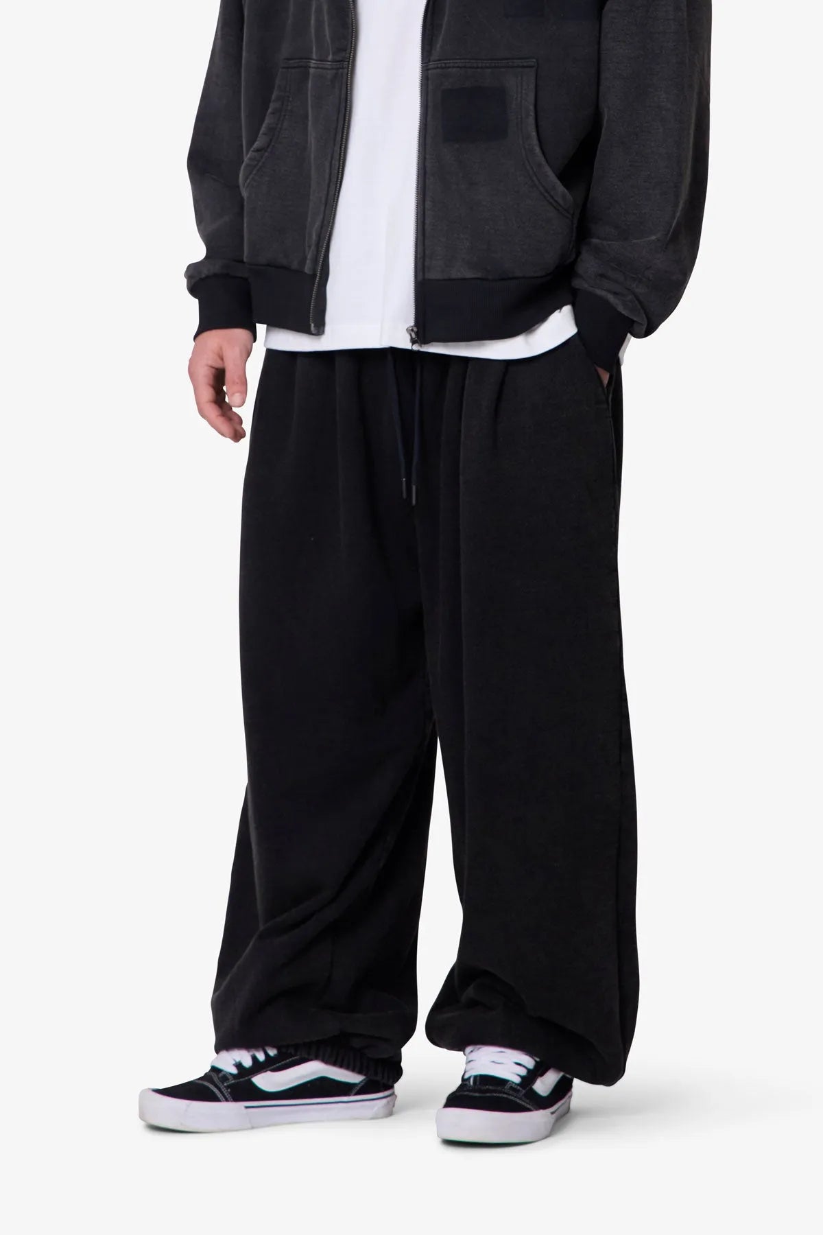 Person wearing black baggy sweatpants with a plain background