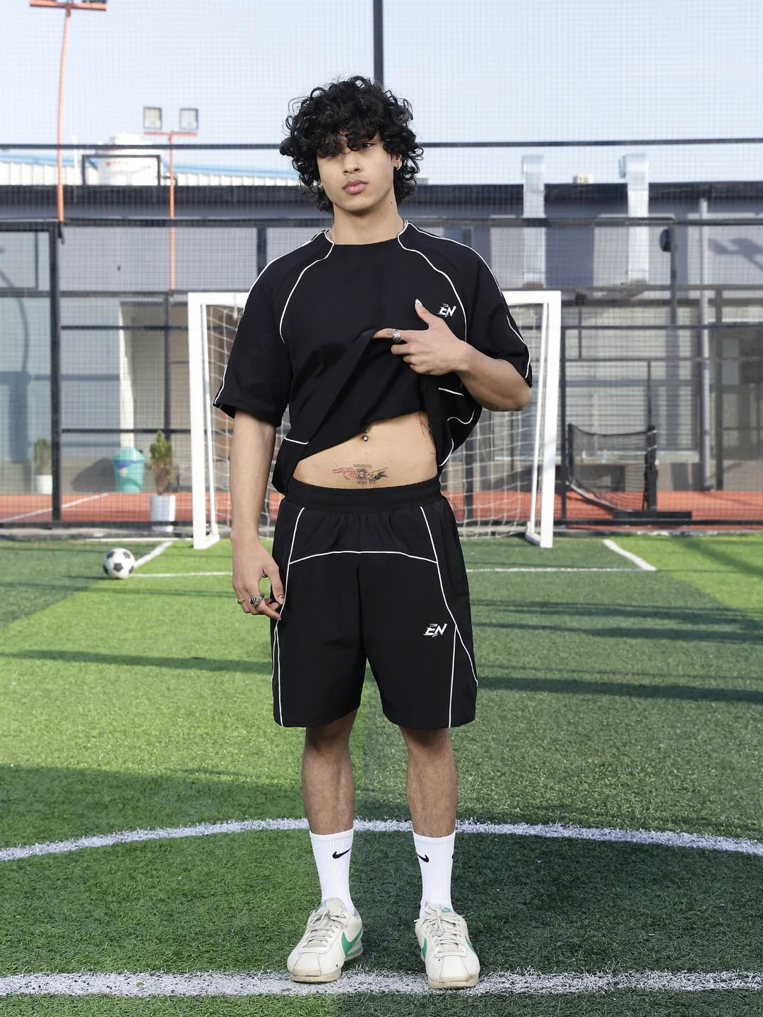 Person wearing a black t-shirt and shorts on a sports field