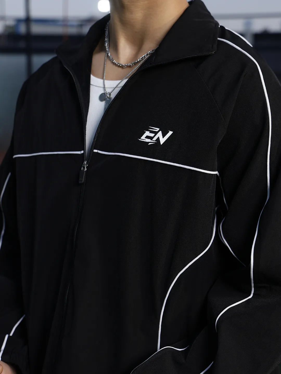 Black sports jacket with a logo on the chest against a blurred background