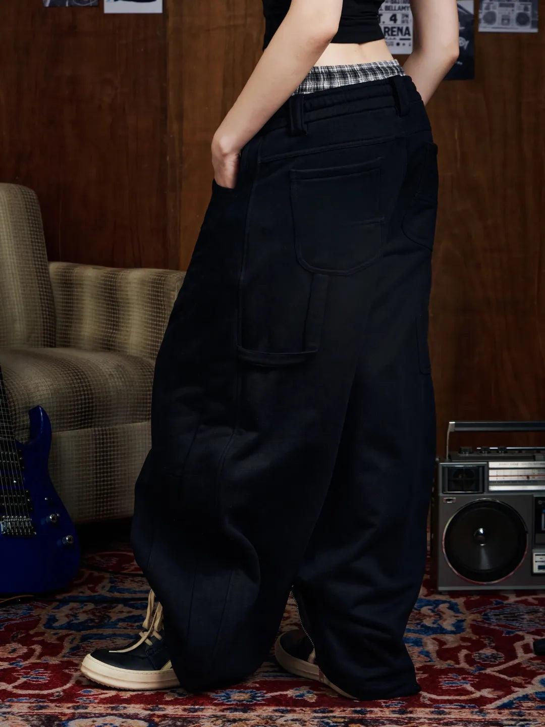 Person wearing black sweatpants in a room with a guitar and stereo equipment.